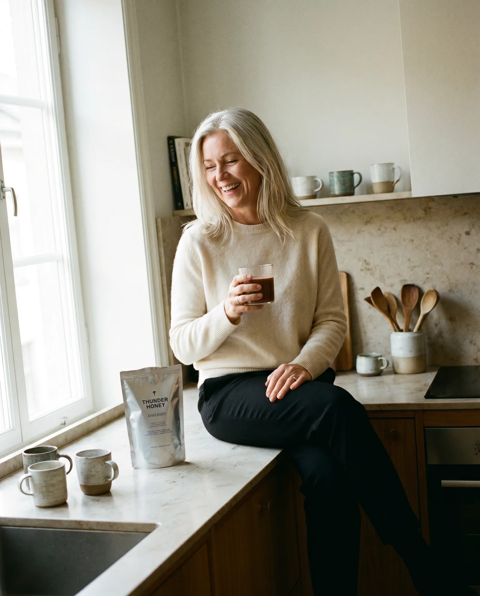 A composed woman in her 50s with a warm mug, the perimenopausal Thunder Honey Daylight drinker who swapped coffee for no-added-caffeine cacao