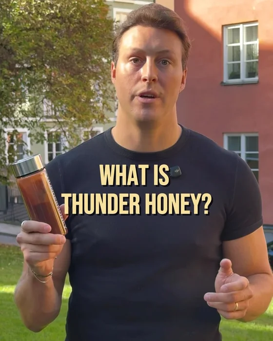 A man in a Thunder Honey t-shirt outdoors holding a glass bottle of cacao, with the words What is Thunder Honey?