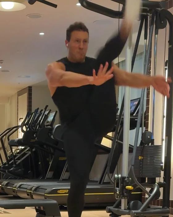 A man doing a high kick in a home gym
