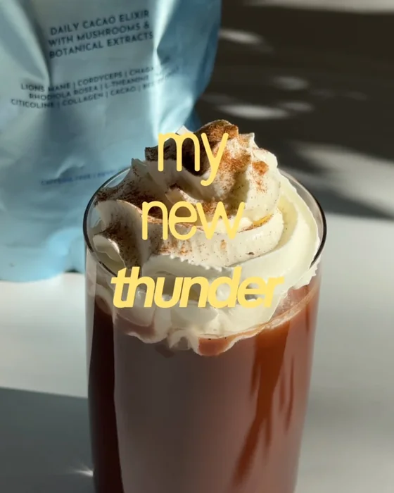 A glass of hot cacao topped with whipped cream and cinnamon in front of a Daylight pouch, with the words my new thunder